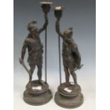 A pair of spelter candlesticks modelled as mythological warriors, 49cm high