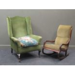 An Edwardian wingback armchair with green upholstert on black painted carbriole front legs and