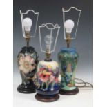 A Moorcroft Orchid pattern table lamp and two others tallest 37cm high (without fitting)