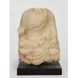 A mottled white marble seated headless Buddhist deity, perhaps 6th/7th century,