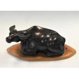 A Chinese black striated stone model of a recumbent water buffalo, late Qing circa 1900,