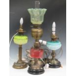A collection of oil lamps, some converted for electricty, with green, blue and red glass
