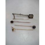 A memorial hat pin tested as 9ct gold, a garnet stick pin tested as 9ct gold, and a wishbone stick