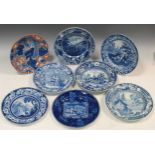 A collection of twelve pottery blue and white plates and dishes, with various landscape,