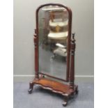 A Victorian mahogany cheval mirror, the rounded arched mirror within a pair of turned column