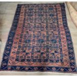 A Belouch wool tribal rug with madder field with three rows of blue lozenges and a double undulating