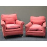 A near pair of early late 19th/ early 20th century deep armchairs with salmon coloured upholstery (