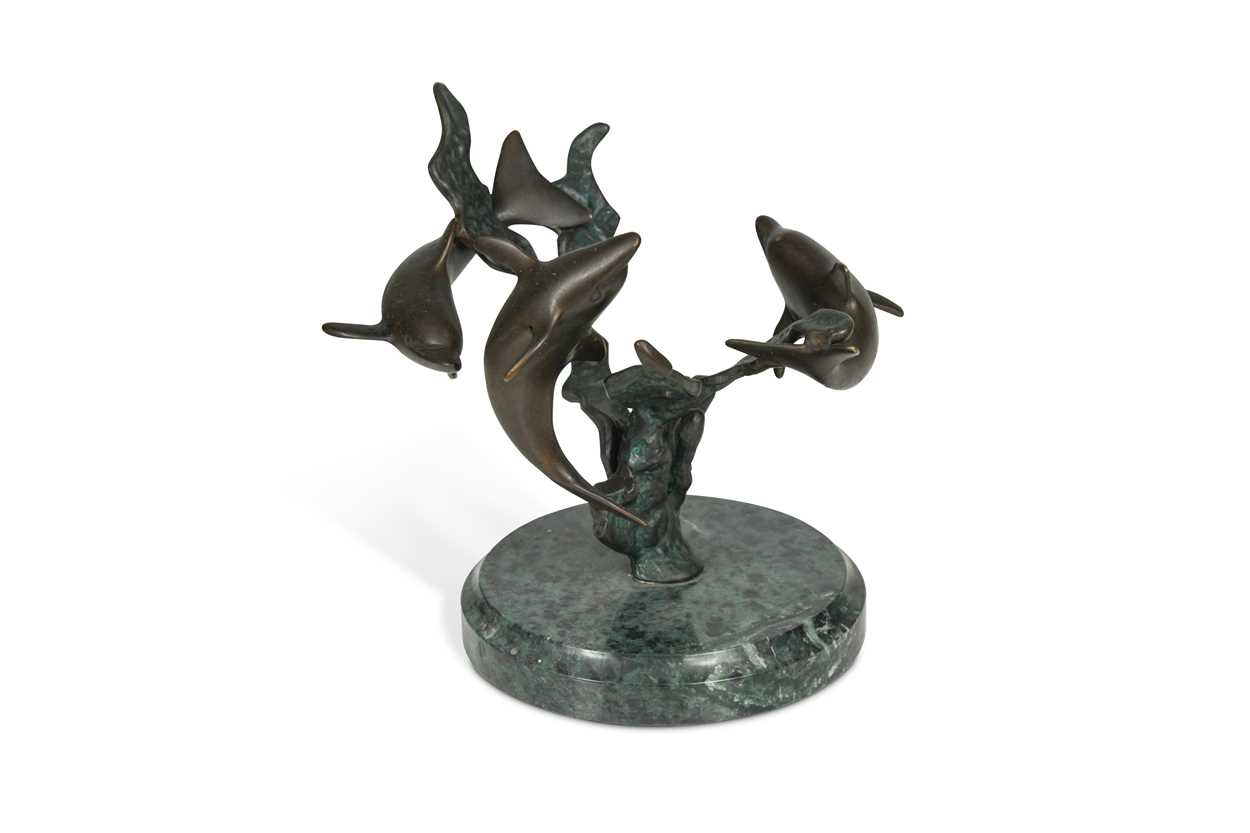 A bronze model of three swimming dolphins, the patinated model mounted to a green marble plinth