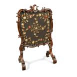 A mid-Victorian walnut fire screen, the carved walnut frame in the rococo style decorated with C-