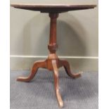A George III style mahogany and oak tripod table, the circular tilt top over a turned column support