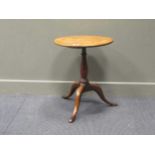 A small George III oak tripod table, the circular top over a turned baluster support raised on