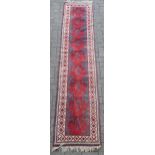 A red ground runner, with diamond pattern border 280 x 61cm