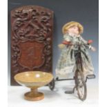 A marble pedestal bowl, together with a porcelain doll on a bicycle, a carved oak heraldic panel and