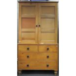 A pine dresser with ebony handles, the wardrobe top section upon the lower section of two short