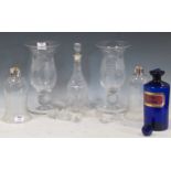 Two engraved glass vases, together with two glass shades, a large blue glass medicine bottle, and