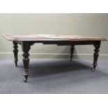 A Victorian mahogany dining table, the rounded rectangular top with two additional leaves raised
