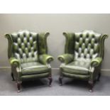 A pair of wing back armchairs with green faux-leather upholstery on short cabriole legs (2)Hawks