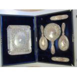 A cased dressing table set comprising silver backed hand mirror, two hairbrushes, two clothes