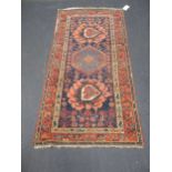 A woolen blue ground rug with red border and geometric design, 194 x 100cm
