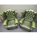 A pair of wing back armchairs with green faux-leather upholstery on short cabriole legs (2)Hawks