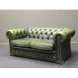 A modern button back Chesterfield type two seater sofa upholstered in green faux-leather, 67 x 160 x