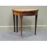 A mid-18th century mahogany demi-lune tea table, the fold-over top raised on tapered legs and pad