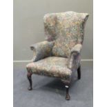 A wingback armchair upholstered in William Morris style fabric on cabriole front legs
