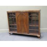 A 1920s mahogany low bookcase cabinet with central cupboard door flanked by a pair of glazed