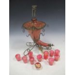 A cranberry glass and gilt cornucopia drinks dispenser with matched cranberry glass miniature
