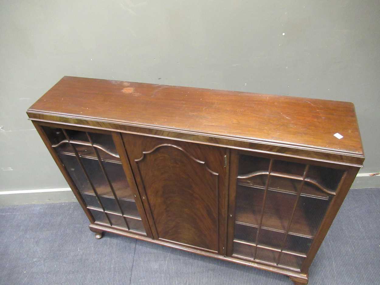 A 1920s mahogany low bookcase cabinet with central cupboard door flanked by a pair of glazed - Image 2 of 5