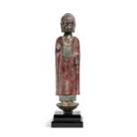 A Chinese painted and parcel gilt grey stone standing figure of Buddha, in Northern Wei style,