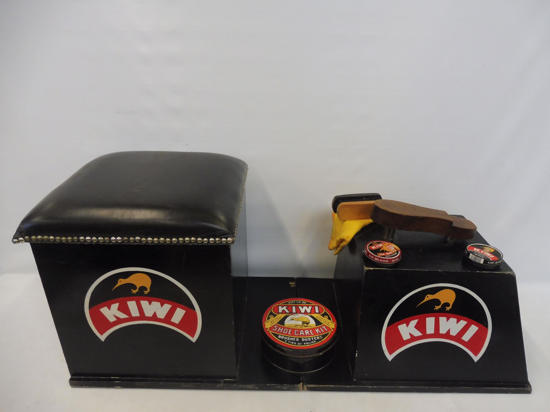 A shoe shine stand with KIWI polish advertising to the sides, plus a small group of KIWI polish tins