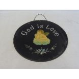 An unusual circular glass sign, bearing the words 'God is Love' with a central angel leaning on a