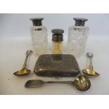 A silver cigarette case, three silver mustard spoons and three silver topped glass bottles.