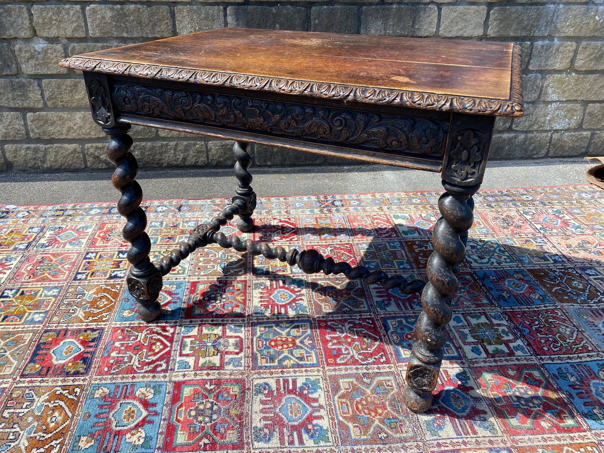 A Victorian carved oak single drawer side table raised upon barley twist supports joined by a