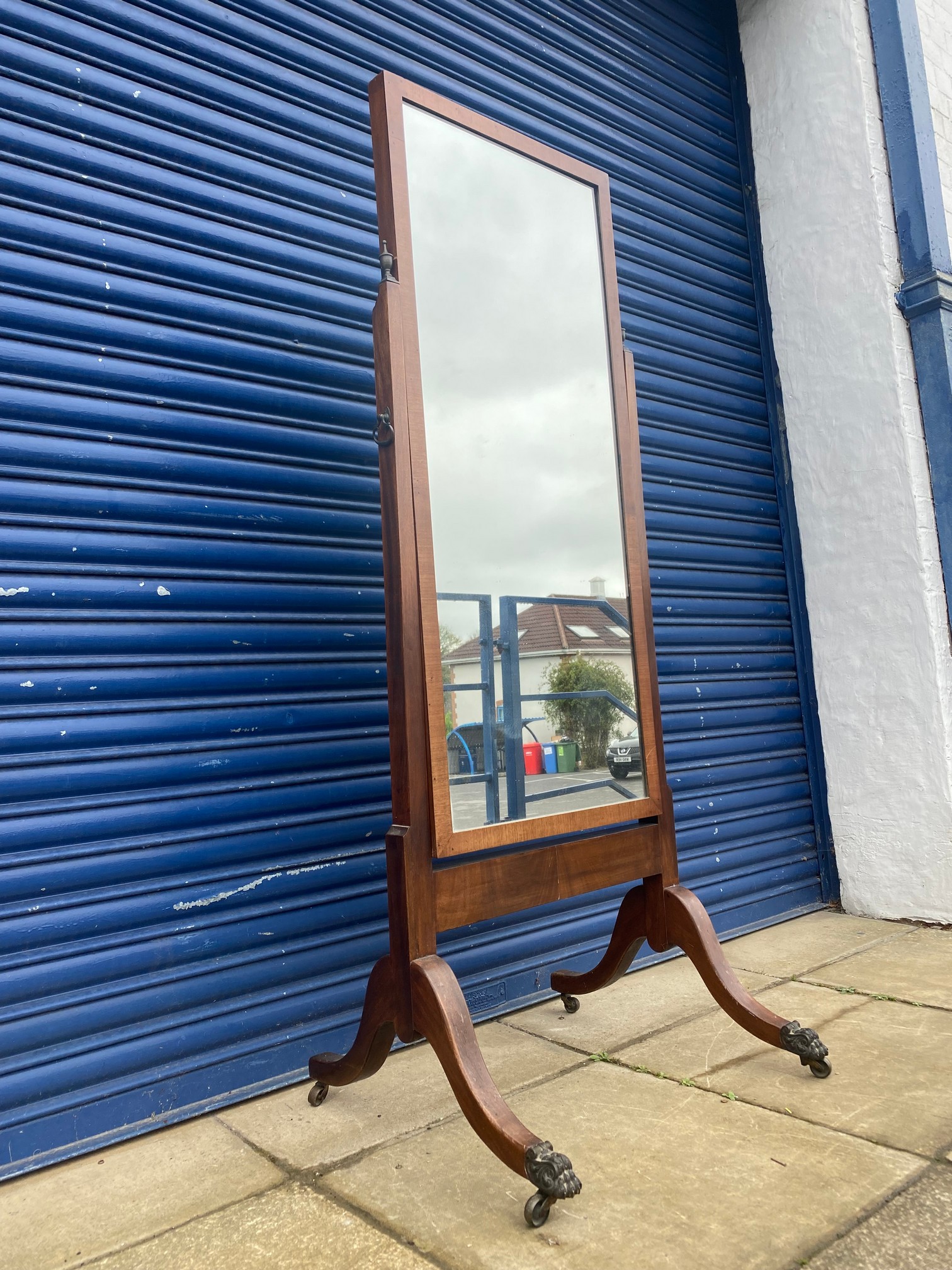 A mahogany cheval mirror of plain rectangular form raised upon swept supports ending in bronze front