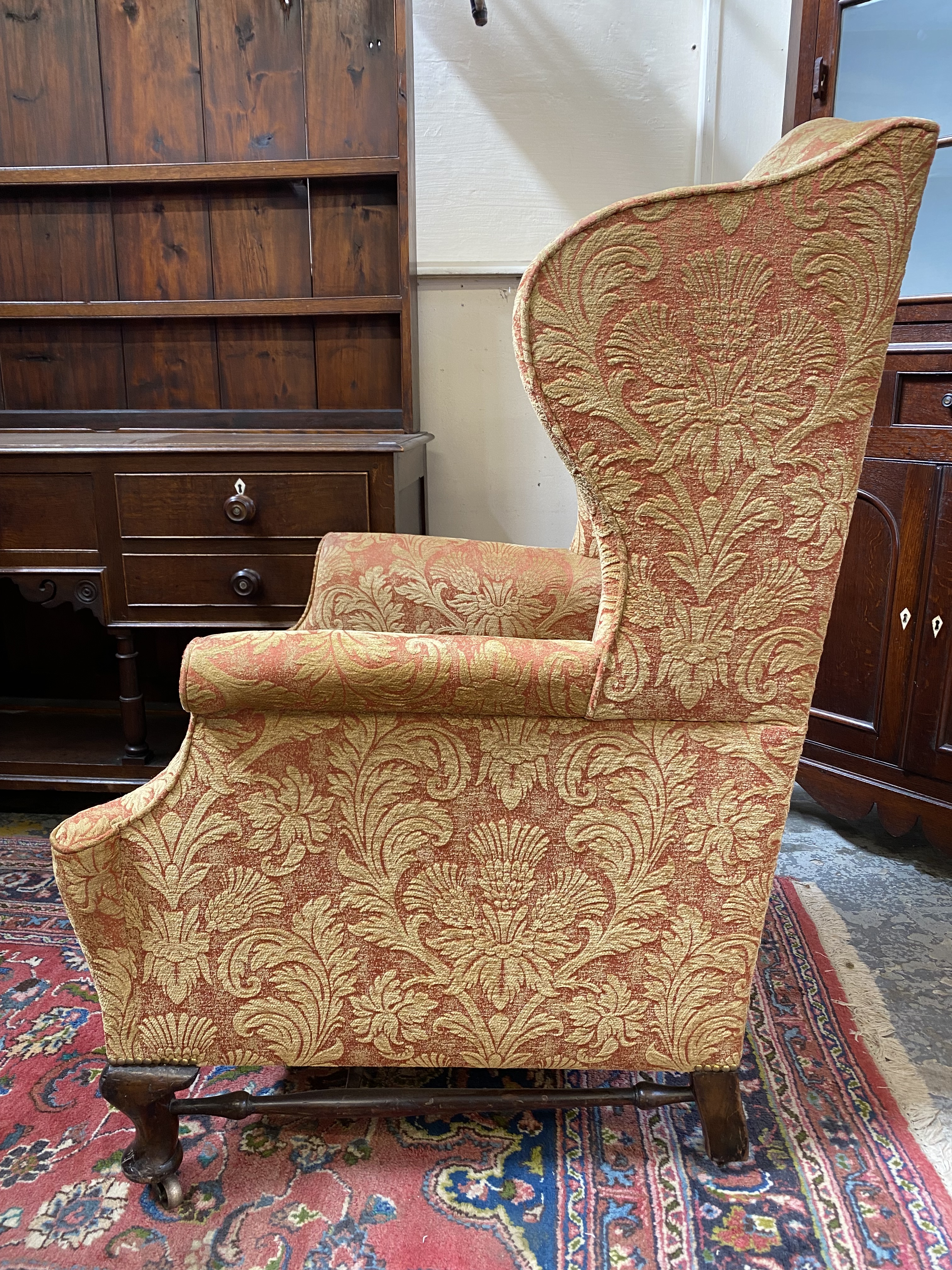 An upholstered wing back armchair raised upon mahogany supports, joined by a stretcher, probably - Image 5 of 7