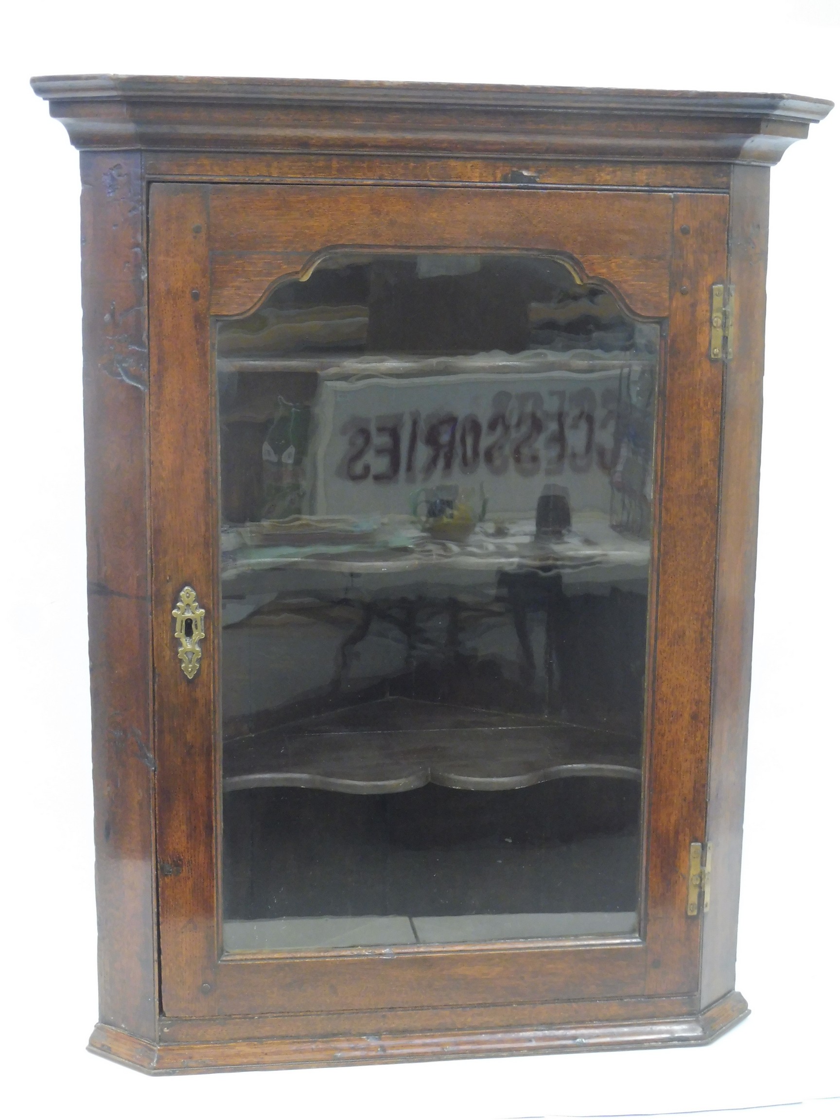 A Georgian oak wall hanging corner cabinet with glazed door enclosing shaped shelves, 29 1/2" wide x