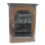 A Georgian oak wall hanging corner cabinet with glazed door enclosing shaped shelves, 29 1/2" wide x