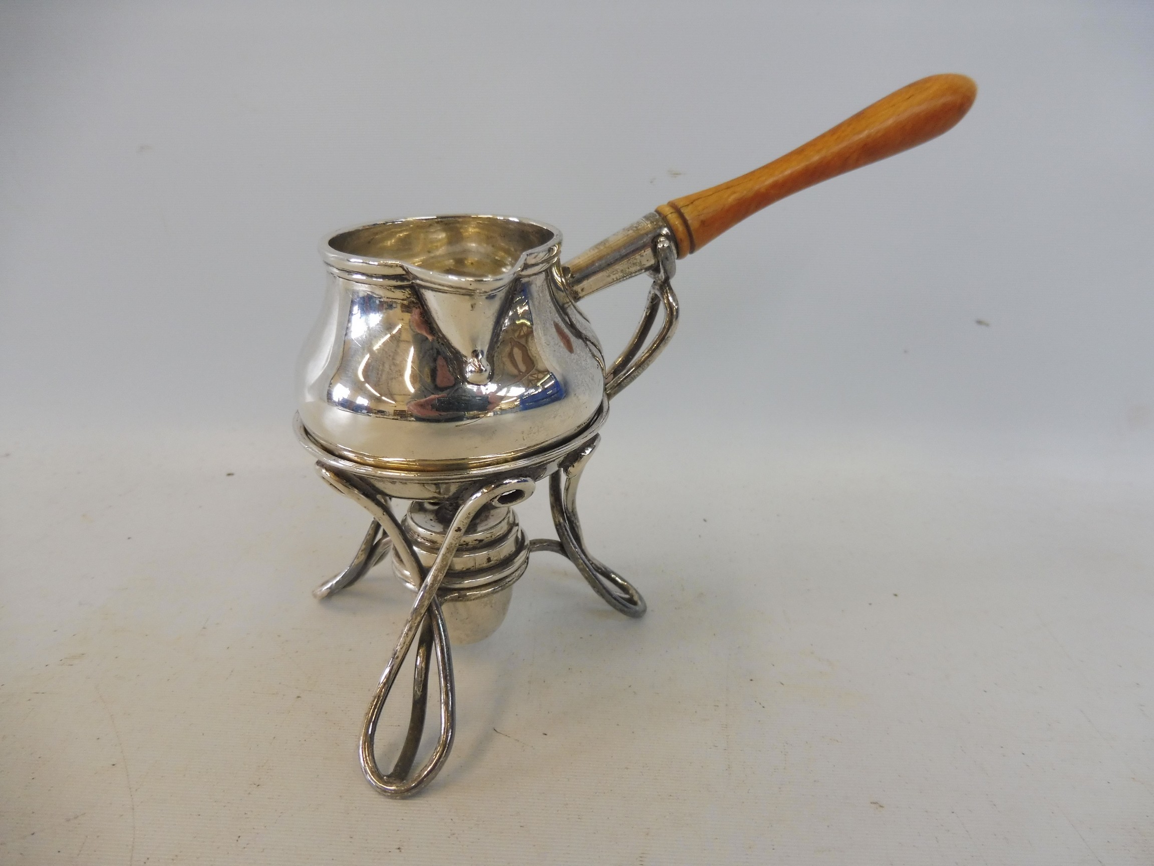 An Art Nouveau style silver miniature brandy saucepan with pouring spout, raised on a spirit