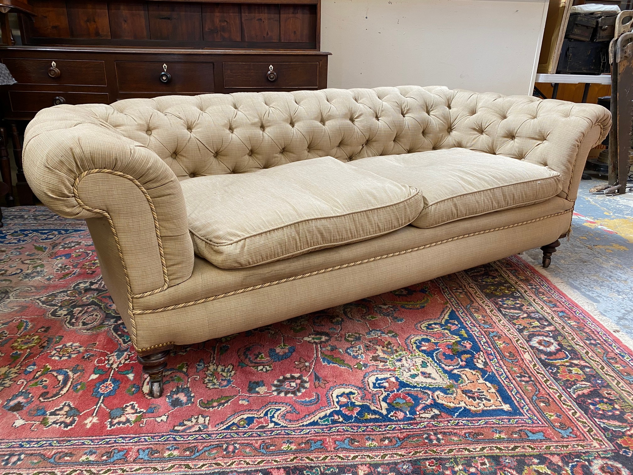 A late Victorian Howard style button back upholstered chesterfield sofa raised upon turned front