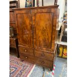 An early 19th Century mahogany linen press of two panelled doors enclosing slides, above a three