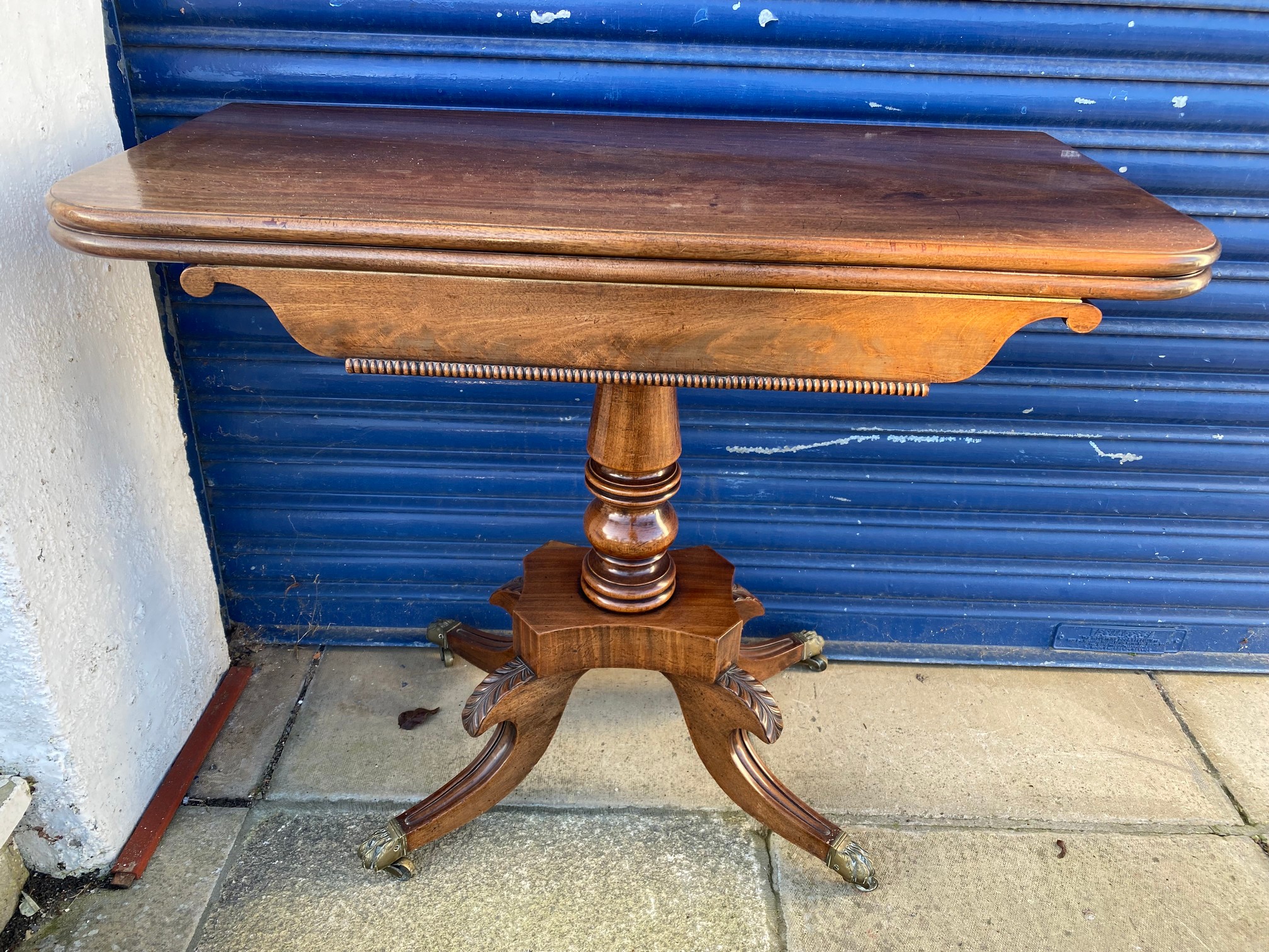 An early 19th Century mahogany fold over card table, raised upon a turned stem to splayed supports.