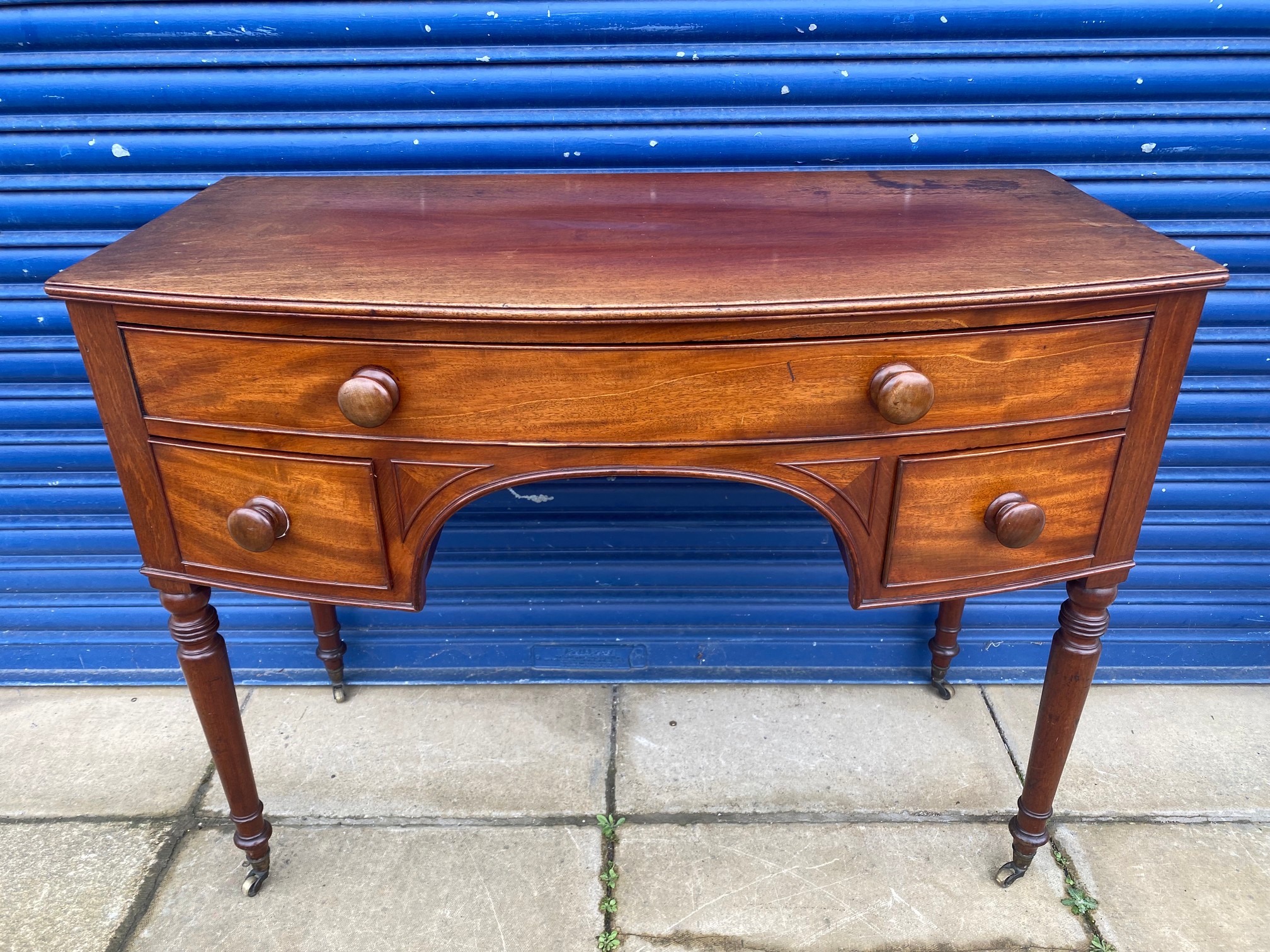 An early 19th Century mahogany bow fronted desk of a single drawer above two smaller drawers, raised