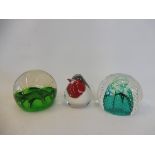 Three glass paperweights, one in the form of a bird.