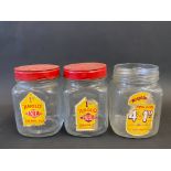 Three glass chewing gum dispensing jars, two with lids.