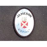 A wooden framed oval mirror with applied lettering advertising Jameson Whiskey, 22 1/2 x 32 1/2".