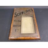 A brass fronted pub menu holder with lift up front, advertising Schweppes Soda Water Etc.,