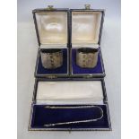 A pair of cased silver napkin rings, by Wakely & Wheeler, London 1964/5, plus a cased pair of