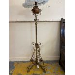 An Arts & Crafts brass standard lamp on three scrolled legs, the oil lamp converted to